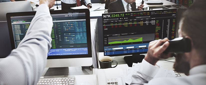 Traders in front of monitors with forex data, transitioning to become an Introducing Broker.