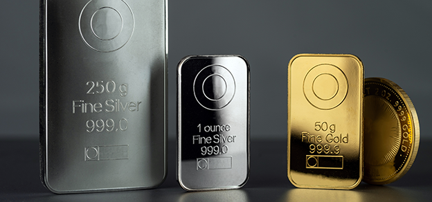 two silver and a gold bar next to a coin referring to how to trade CFDs on gold and silver
