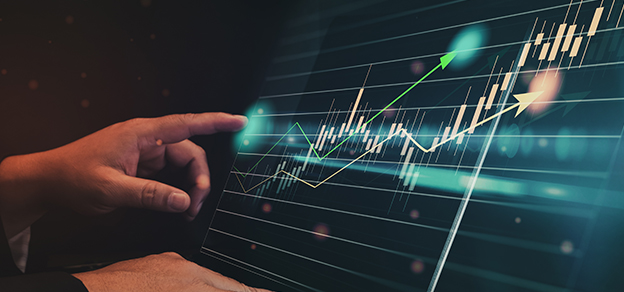 a hand pointing to a laptop screen with candlestick charts relating to forex trade ideas