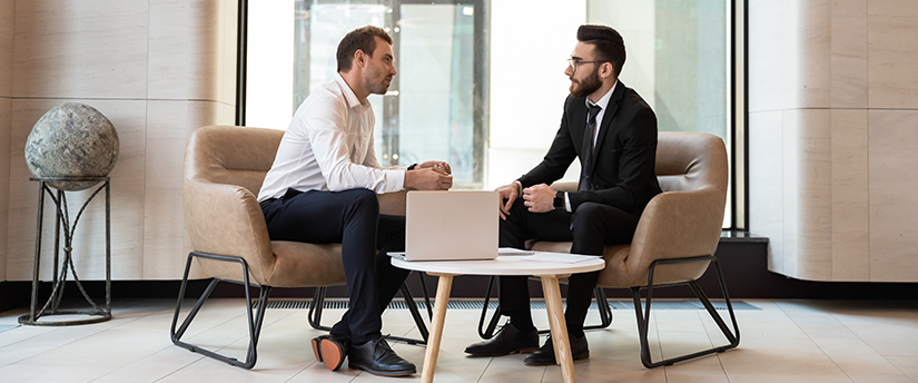Two traders in a discussion with a laptop nearby, exemplifying the collaboration among forex traders.