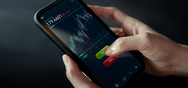 A trader holding a mobile phone with charts displayed, exploring the best days to trade in the financial markets.