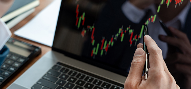 A professional forex trader, intently focused on candlestick charts on his laptop, demonstrates the key role of analysis in currency trading.
