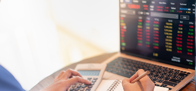 A professional forex trader, with a laptop and calculator before him, showcases the analytical and data-driven approach to currency trading.