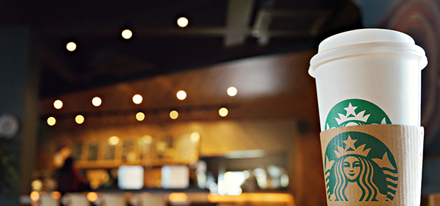 A Starbucks cup with the logo and a store in the background, symbolizing the coffee brand and its physical locations."