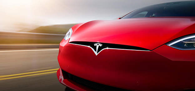 a red Tesla (TSLA) car on the road with the desert in the background