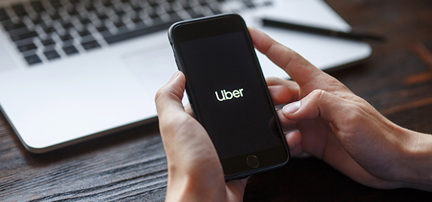 Someone holding a mobile device with the Uber logo, illustrating the ride-sharing and transportation service.