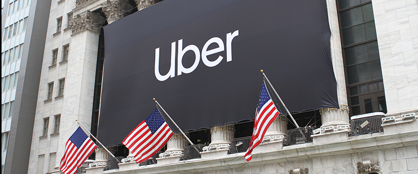 The Uber sign displayed on a building alongside American flags, representing the presence of the ride-sharing service in the United States.