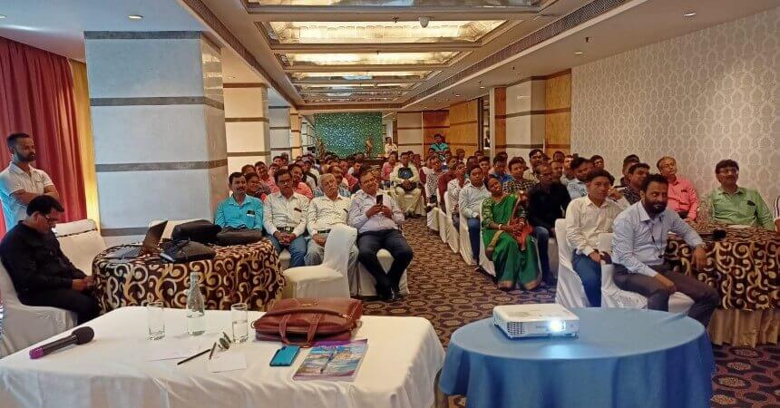 A diverse group of individuals sitting in a conference room, attentively listening to a speaker.