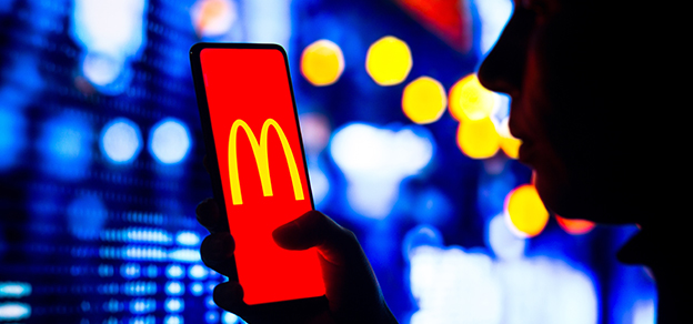 Holding a phone with the McDonald's logo, with a glowing background, emphasizing the brand's recognition and presence.