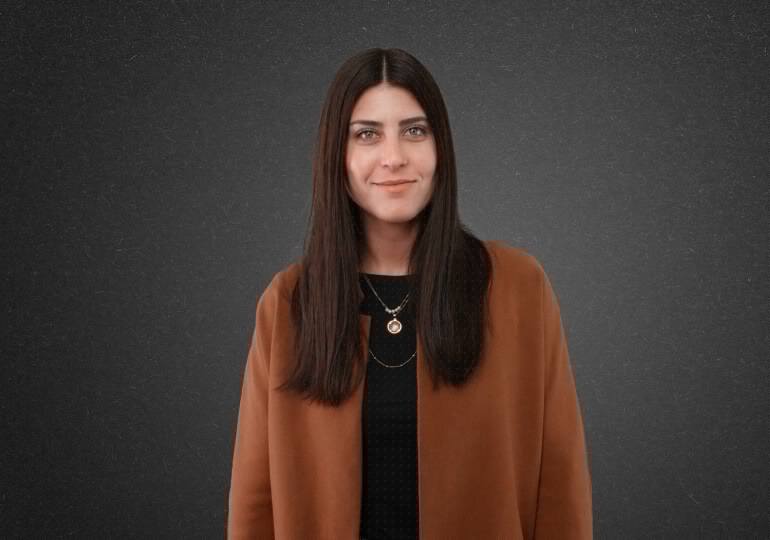 Woman with long hair in brown jacket.