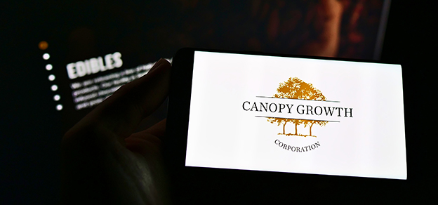 A user holding a mobile device featuring the Canopy Growth logo, bridging technology and the cannabis industry.