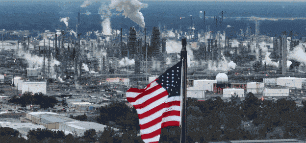 An American flag in front of a refinery, symbolizing Exxon Mobil's presence in the energy and oil industry.