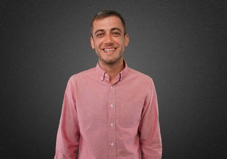 A man in a pink shirt smiling