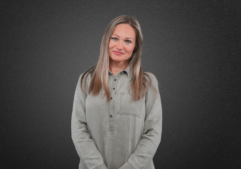 Woman with long hair wearing a grey shirt.