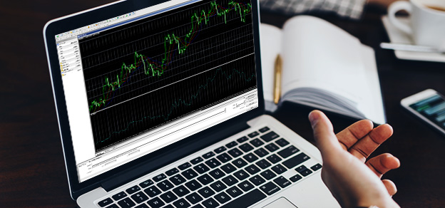 A trader, hunched over a laptop running MetaTrader 4, utilizes charting tools to analyze market data and make informed trading decisions.