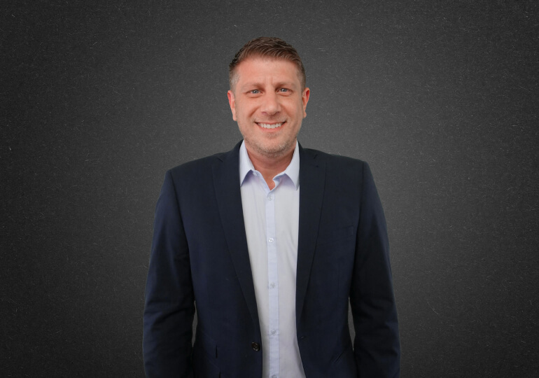 A professional man wearing a suit and tie with a pleasant expression on his face.