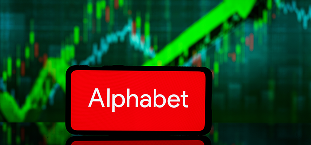 A mobile device featuring the Alphabet (Google) logo with a board of candlestick charts in the background, blending technology and finance.
