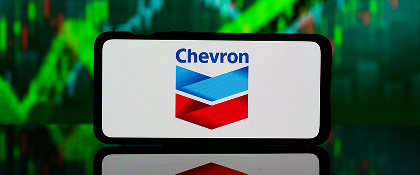 A mobile device displaying the Chevron logo, surrounded by charts, symbolizing technology and data in the energy industry.
