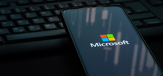 a mobile phone displaying Microsoft logo and it is leaning against a keyboard.