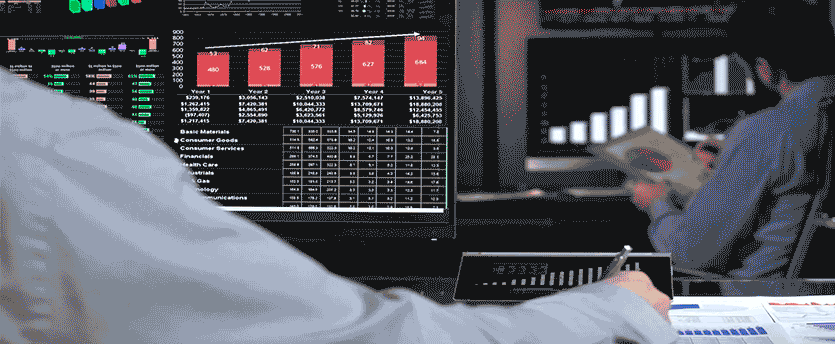 A trader taking notes while analyzing forex data on his laptop, highlighting the utility of a trading platform.