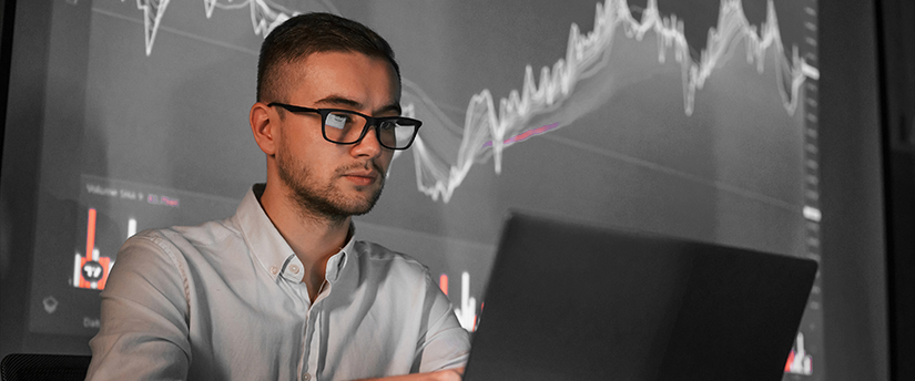 a man with glasses and a graph in the background depicting forex spread trading strategies