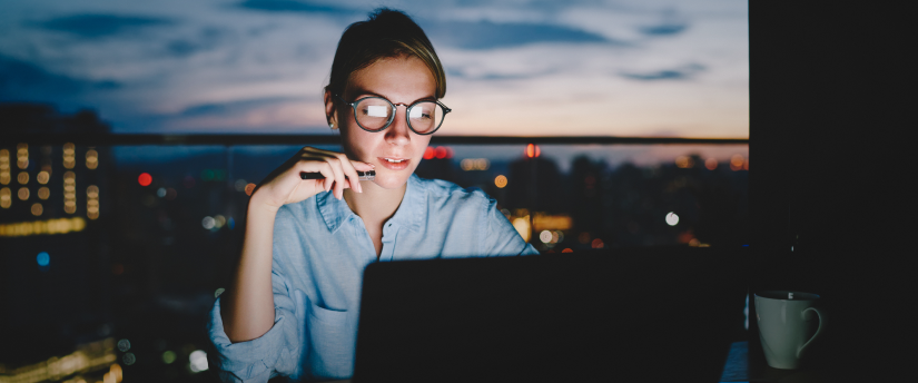 A trader in front of a cityscape, attentively using a laptop, exemplifying the influence of trading psychology.
