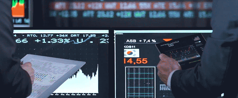 Two traders actively using tablets while monitors display real-time forex data, a scene of dynamic engagement in currency trading.