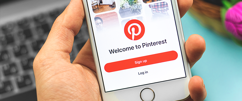 A user holding a phone displaying the Pinterest sign-in page, ready to access the platform's content and features.