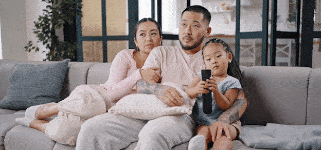 A family seated on their sofa, prepared to enjoy a Netflix viewing experience together.
