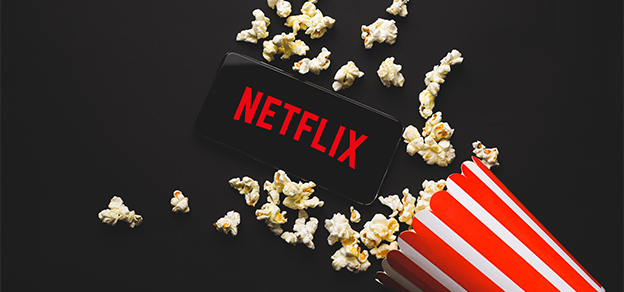 Popcorn next to a mobile device with the Netflix logo, symbolizing entertainment streaming and mobile viewing.