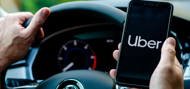 I find myself sitting comfortably in a car, gazing at my mobile device adorned with the distinctive Uber logo, pondering my next destination.