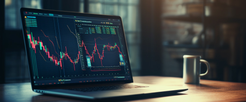 A laptop computer with a CFD stock chart on a wooden table next to a cup of coffee. The laptop is open to a trading platform, and the trader is using a mouse to place a trade.