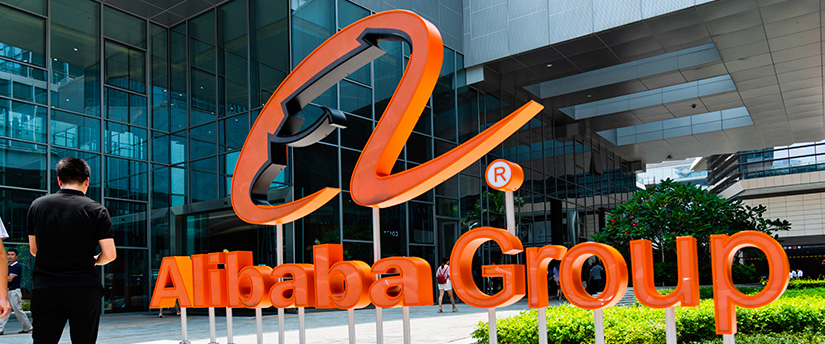 People walking past the Alibaba Group logo outside the building
