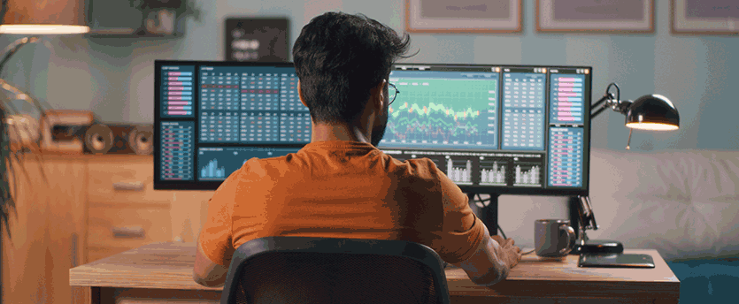 A man at a desk with two monitors, engaged in education, forex trading.