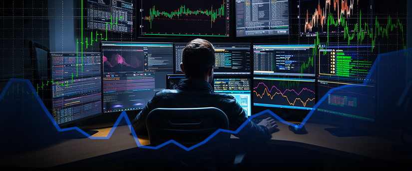 Um comerciante de forex experiente e especializado que analisa dados do mercado de acções em vários ecrãs numa secretária.