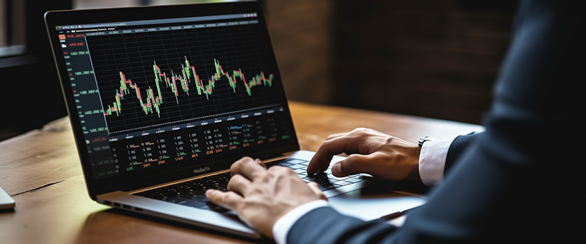 A person in a suit analyzing a stock chart on a laptop.