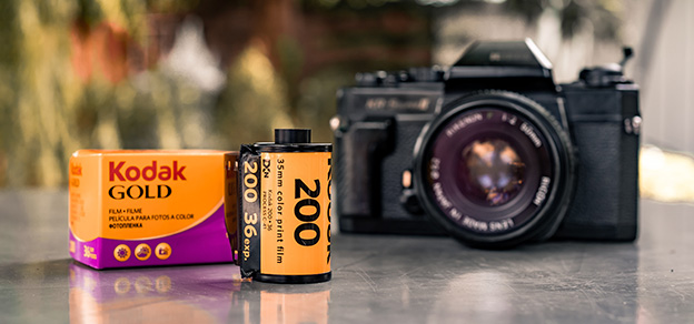 Two film reels and a modern photography machine featuring Kodak signs, encapsulating the blend of classic and contemporary visuals.