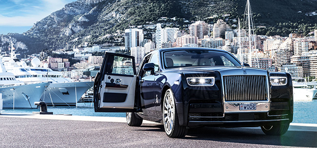 Rolls-Royce luxury car docked in a harbor surrounded by yachts, epitomizing opulence and sophistication by the sea.