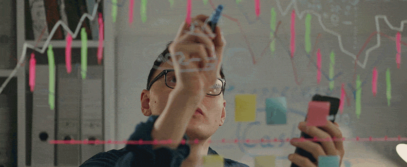 Passionate forex trader writing on whiteboard with marker.
