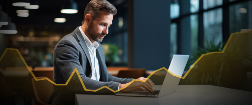 A focused man in a suit intently works on his laptop, engaged in day trading and conducting analysis.