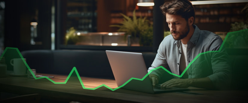 A man trading forex on his laptop, with an upward graph displayed on the screen.
