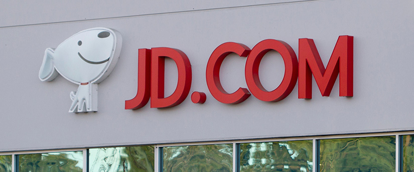 A sign displaying the logo of JD.com is affixed to the side of a building.