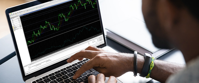A man is engaged in forex trading on his laptop using the MT4 platform.