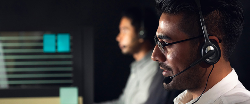 Two men in a call center wearing headsets, providing customer support for forex brokers.