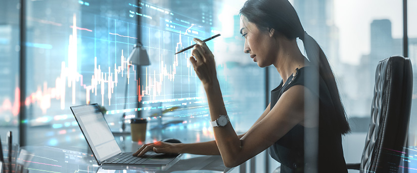 A woman sitting at a desk with a laptop and a pen, using the Metatrader 4 platform.