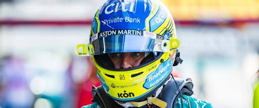 Aston Martin driver wearing a helmet and a blue and yellow suit, ready for an exhilarating ride.