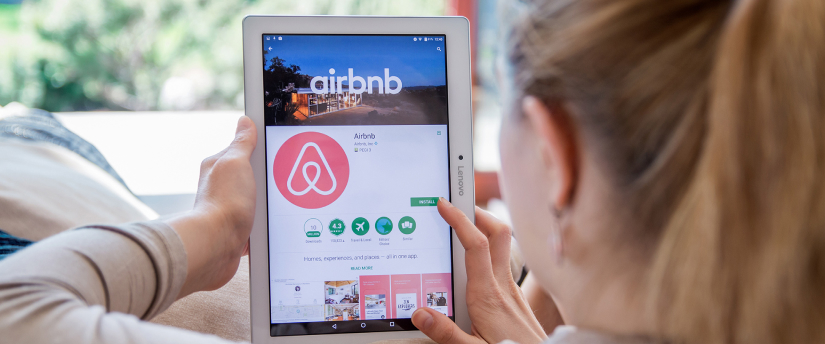 A woman browsing Airbnb app on iPad, representing top short-term rental platform.