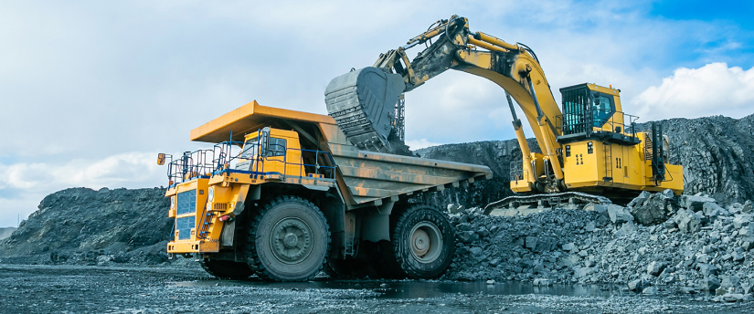 A large dump truck parked next to a large rock on a construction site