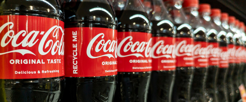 Iconic Coca Cola plastic bottles filled with carbonated soda, featuring red labels.