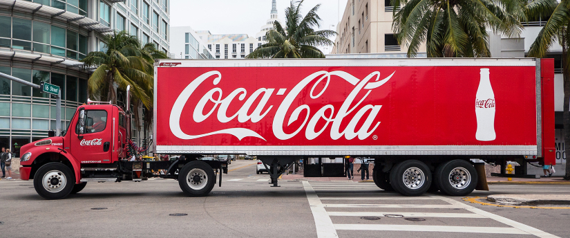 A Coca Cola truck parked in front of a building, showcasing the iconic brand's presence.